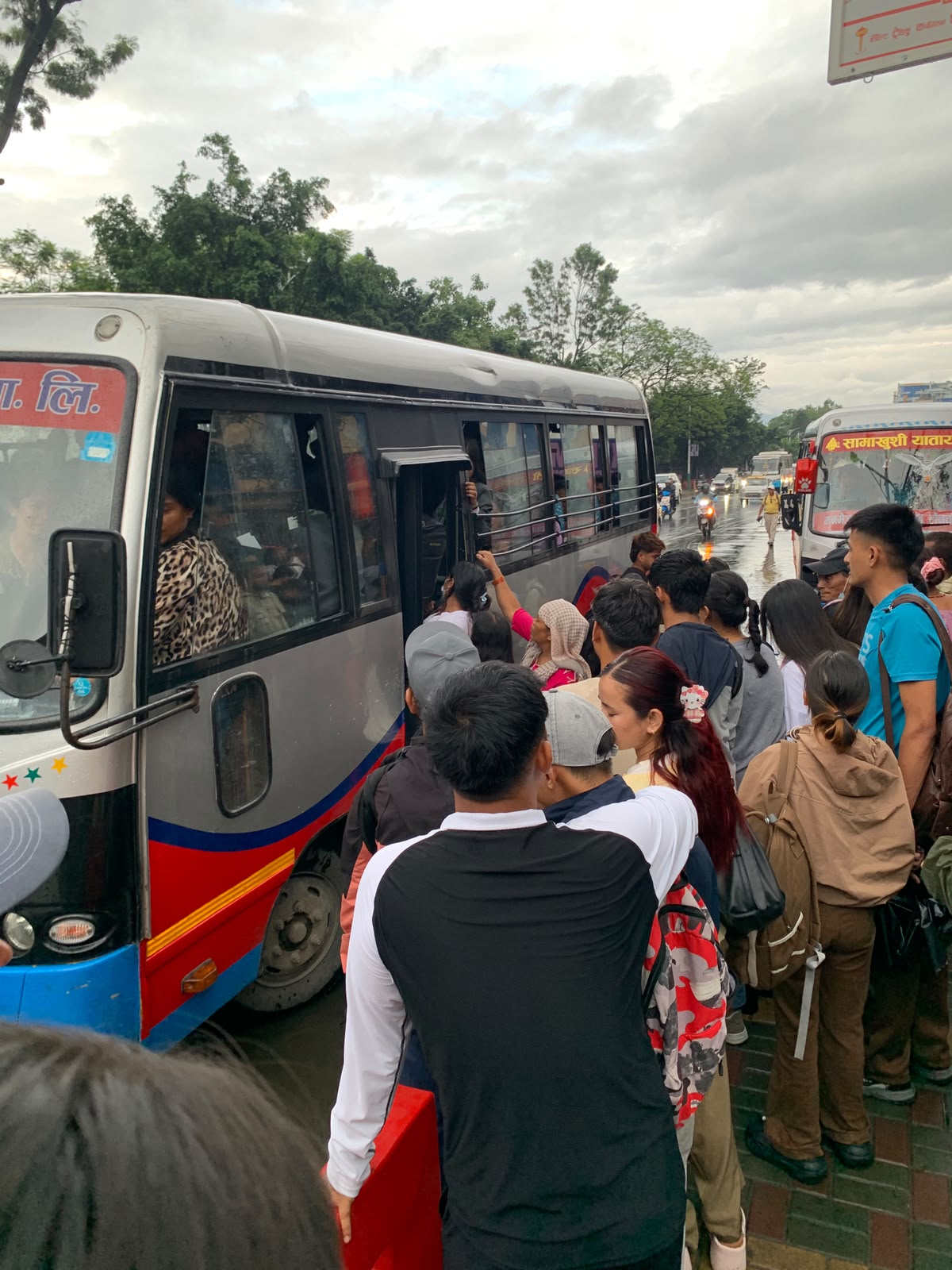 Crowd boarding a bus at Newroad Gate during monsoon rain